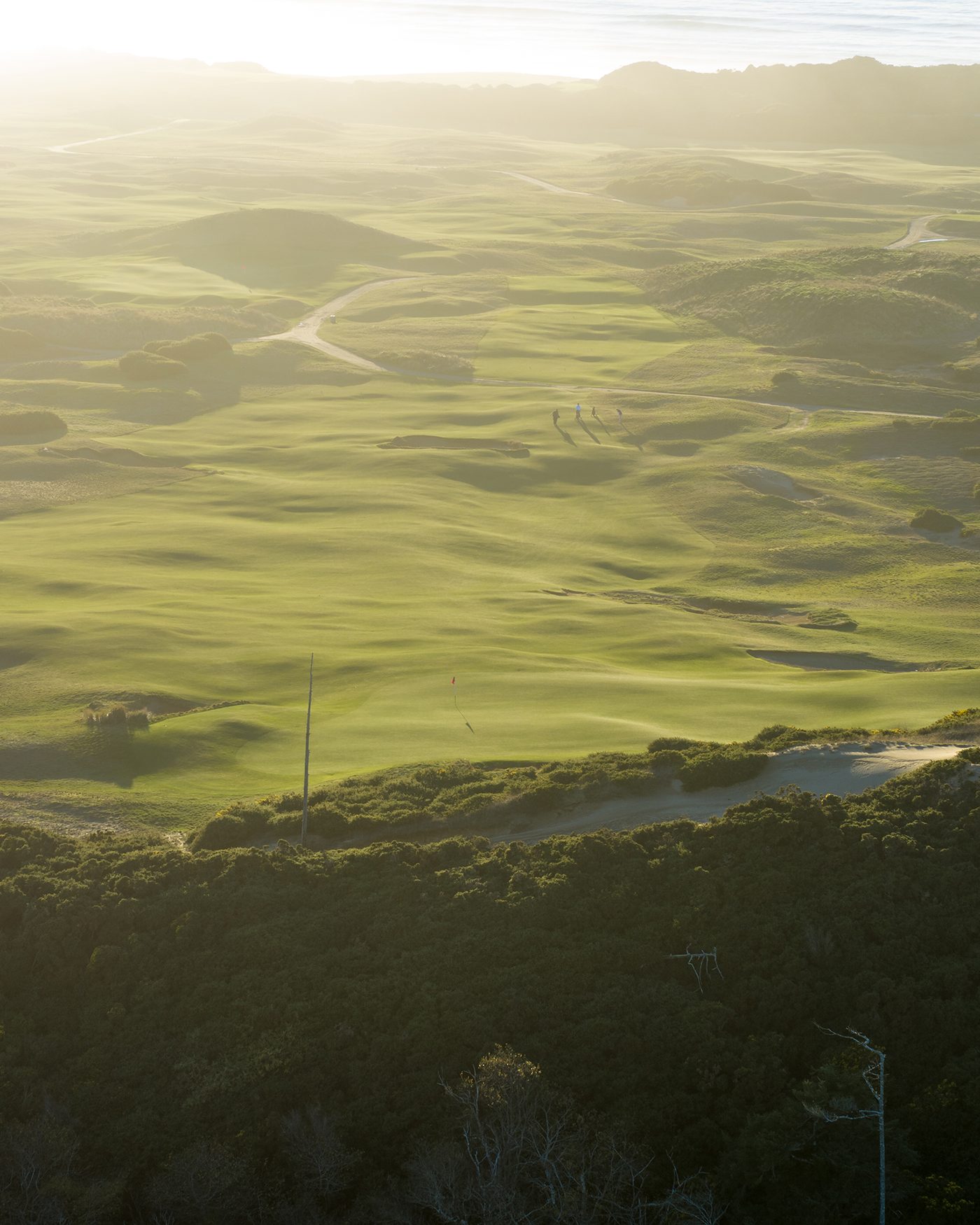 View from a high dune over hazy, sunlit links ground at Old Macdonald