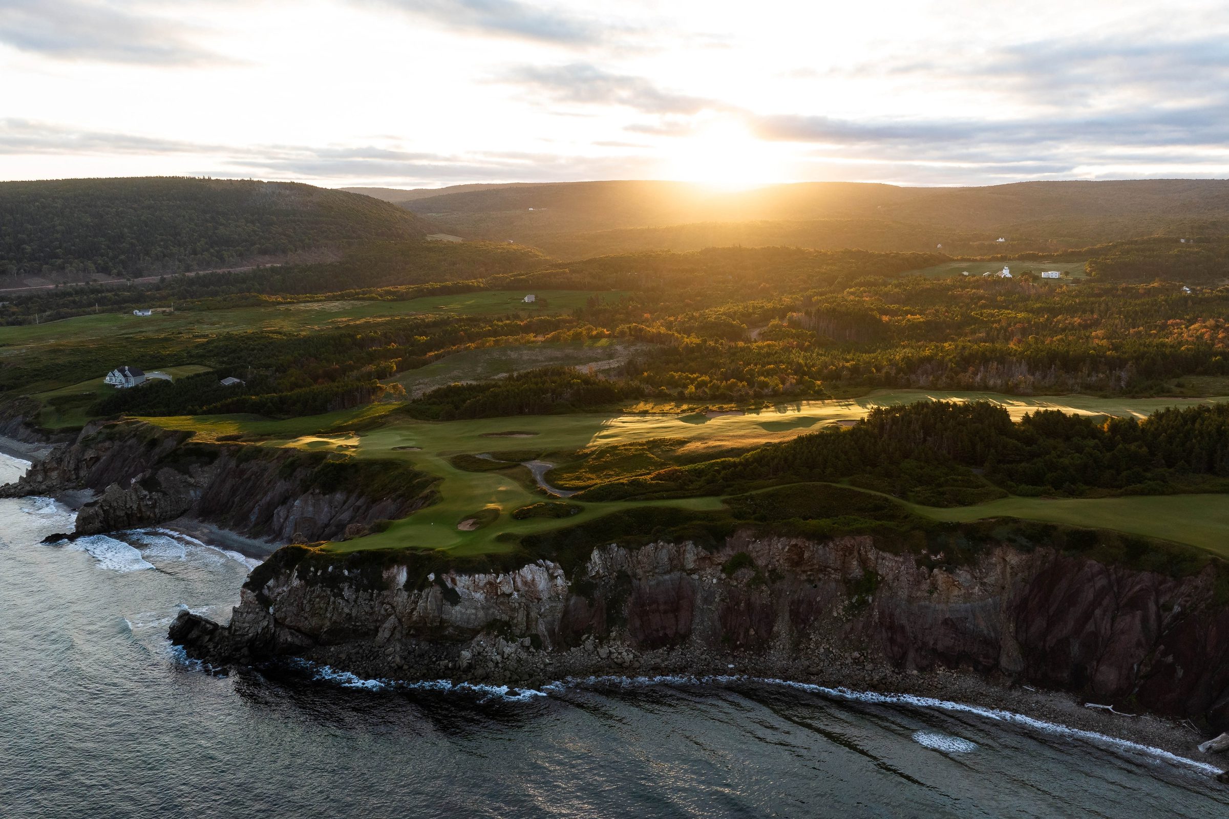 Sunrise over the Cape Breton highlands and a forested valley above the shore