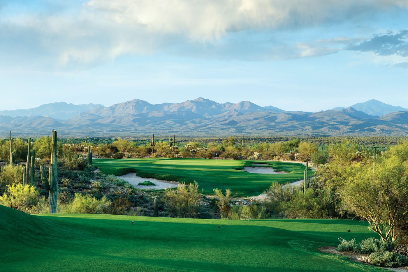 A We-Ko-Pa fairway and green under a big sky with mountains behind