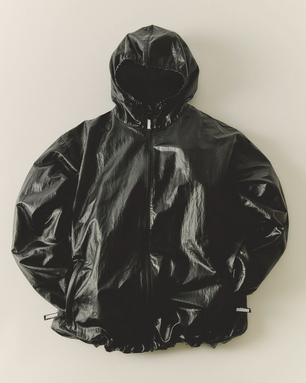 The black Oasis Parka laid flat, showing its faux-leather sheen
