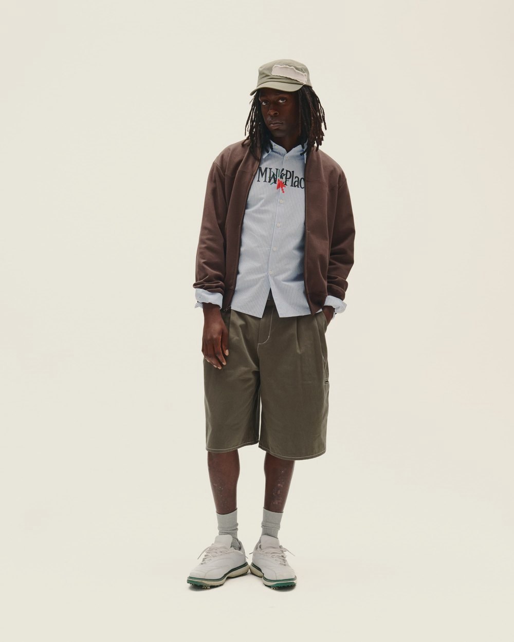 A man in the brown Western Yolk Track Jacket, stripe shirt and olive Buster Shorts
