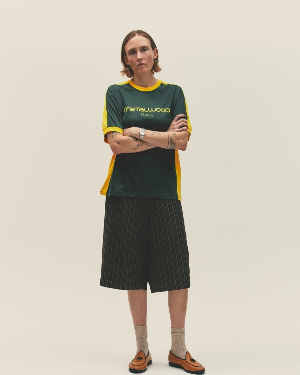 A woman in the green and yellow Creature T-Shirt with black shorts