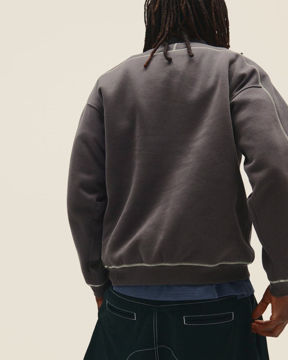 A man seen from behind in a charcoal sweatshirt with contrast stitching