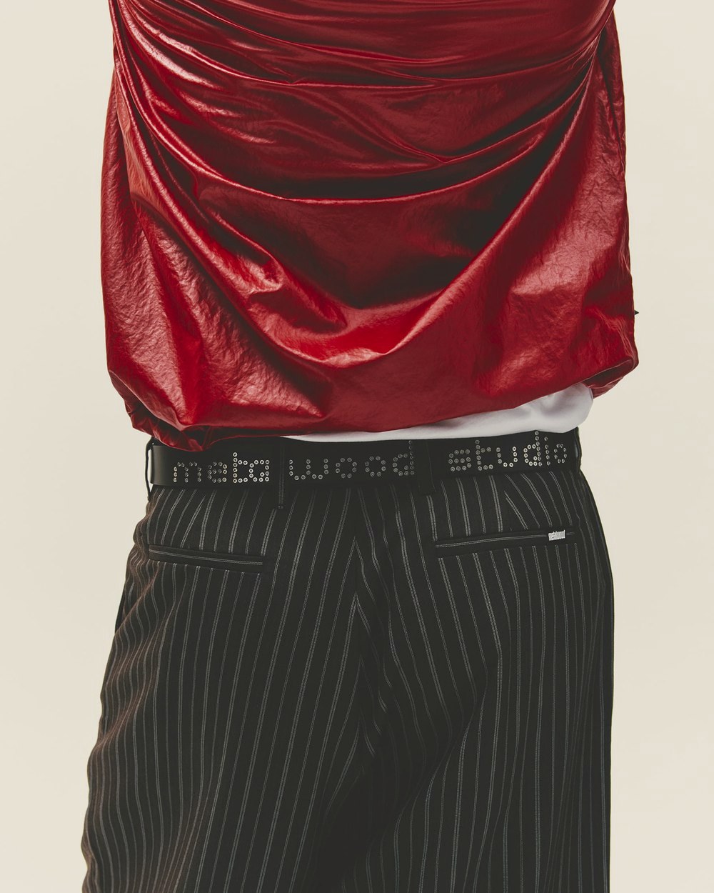 A close-up of a red top over pinstripe trousers with a Metalwood studio waistband