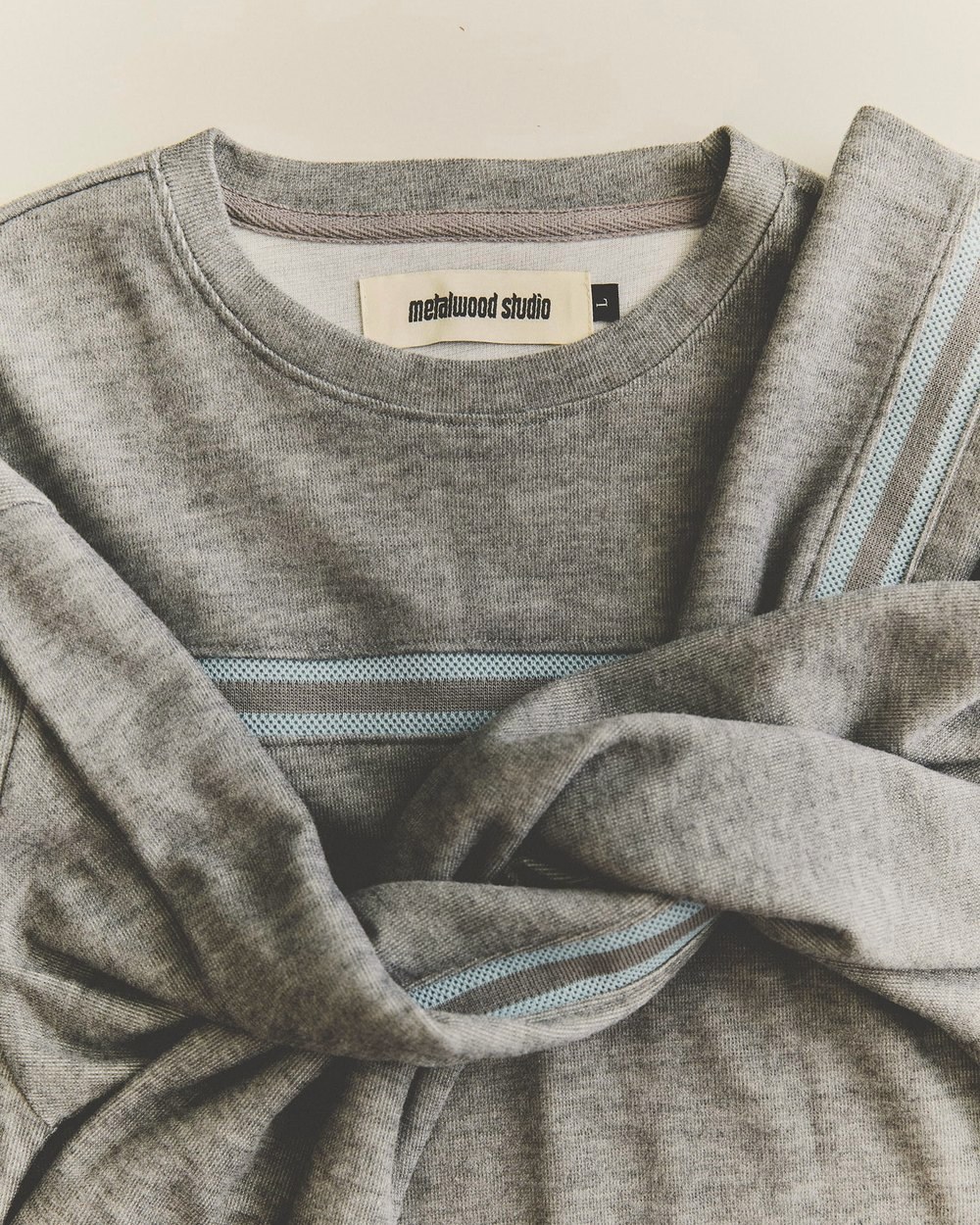 A gray Surf Top with blue tape across the chest, folded