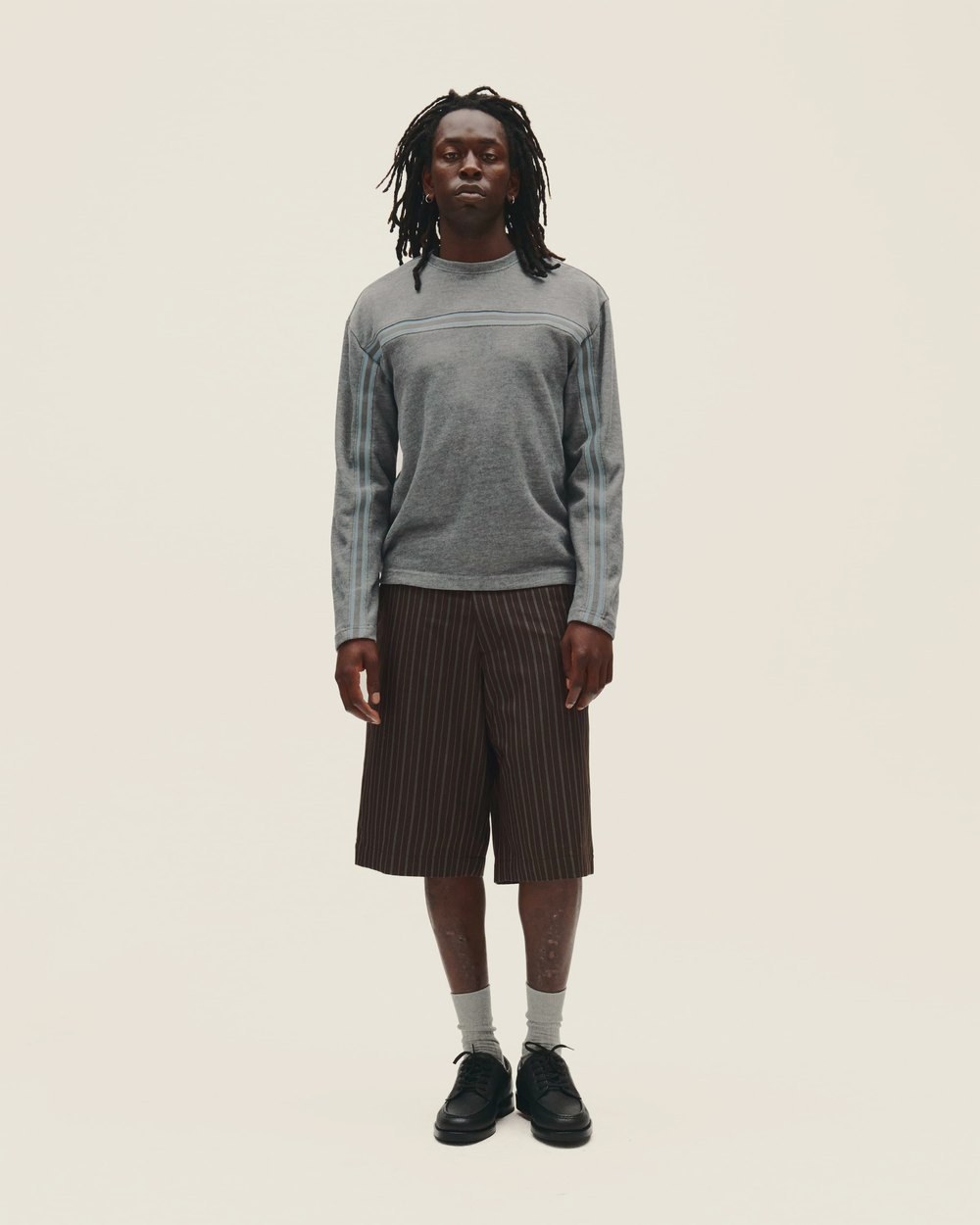 A man in a gray long-sleeve top and brown shorts