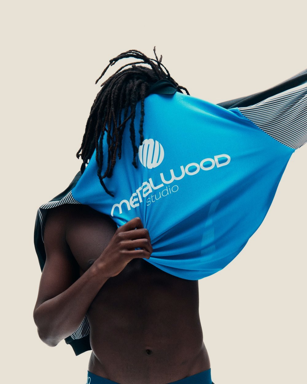 A shirtless man pulling on the blue Goalie Jersey