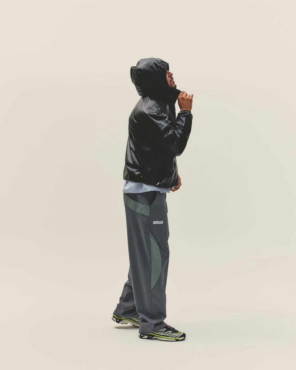 A man in a black hooded jacket and gray pants, looking down