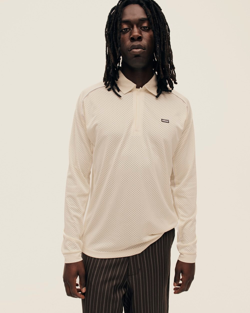 A man in the tan Piped Longsleeve Quarter Zip Polo and pinstripe trousers