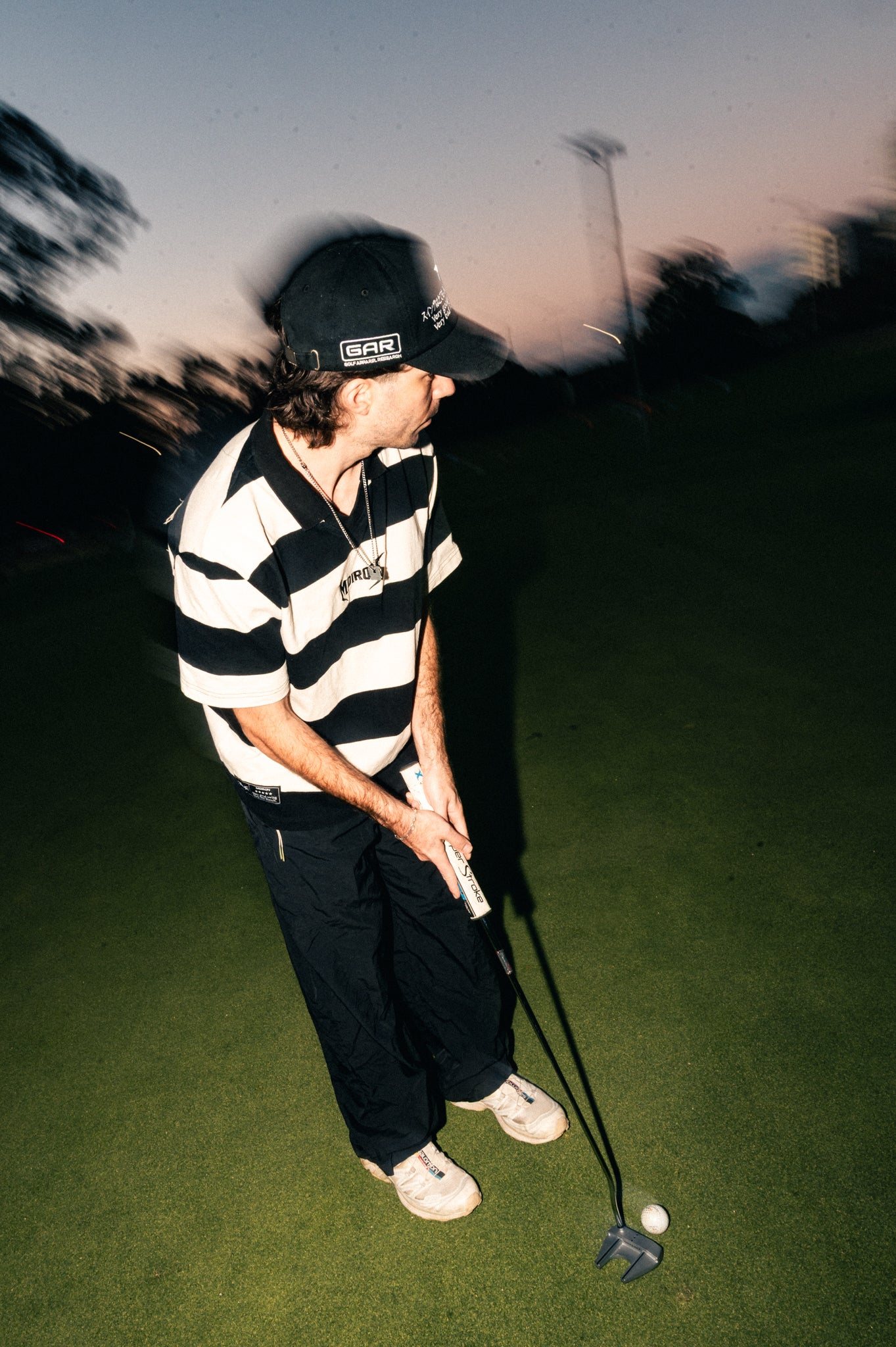 Midiron Detour Stripe Polo in black and cream rugby stripes on a Sydney course at dusk