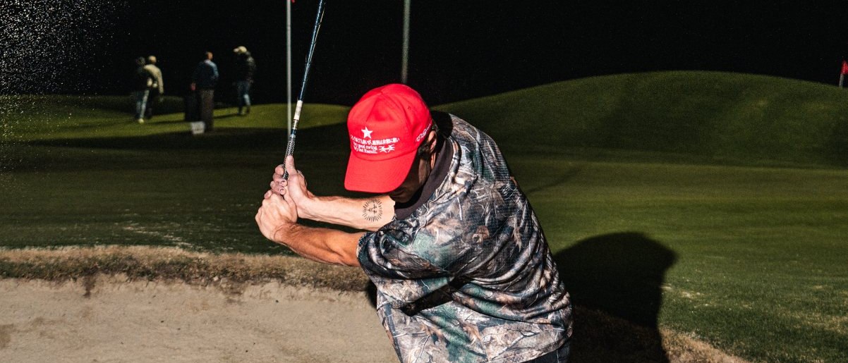Midiron camo golf polo photographed under floodlights on a Sydney par-three course