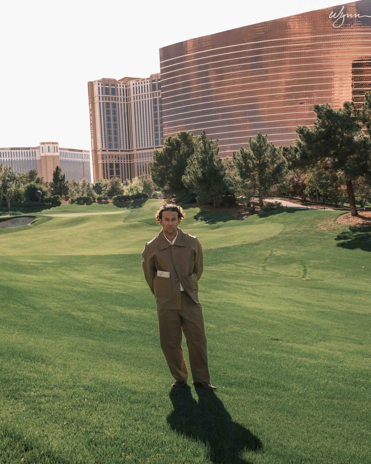 A model in the Gumtree x Wynn work jacket and pants on a fairway with the Wynn tower behind