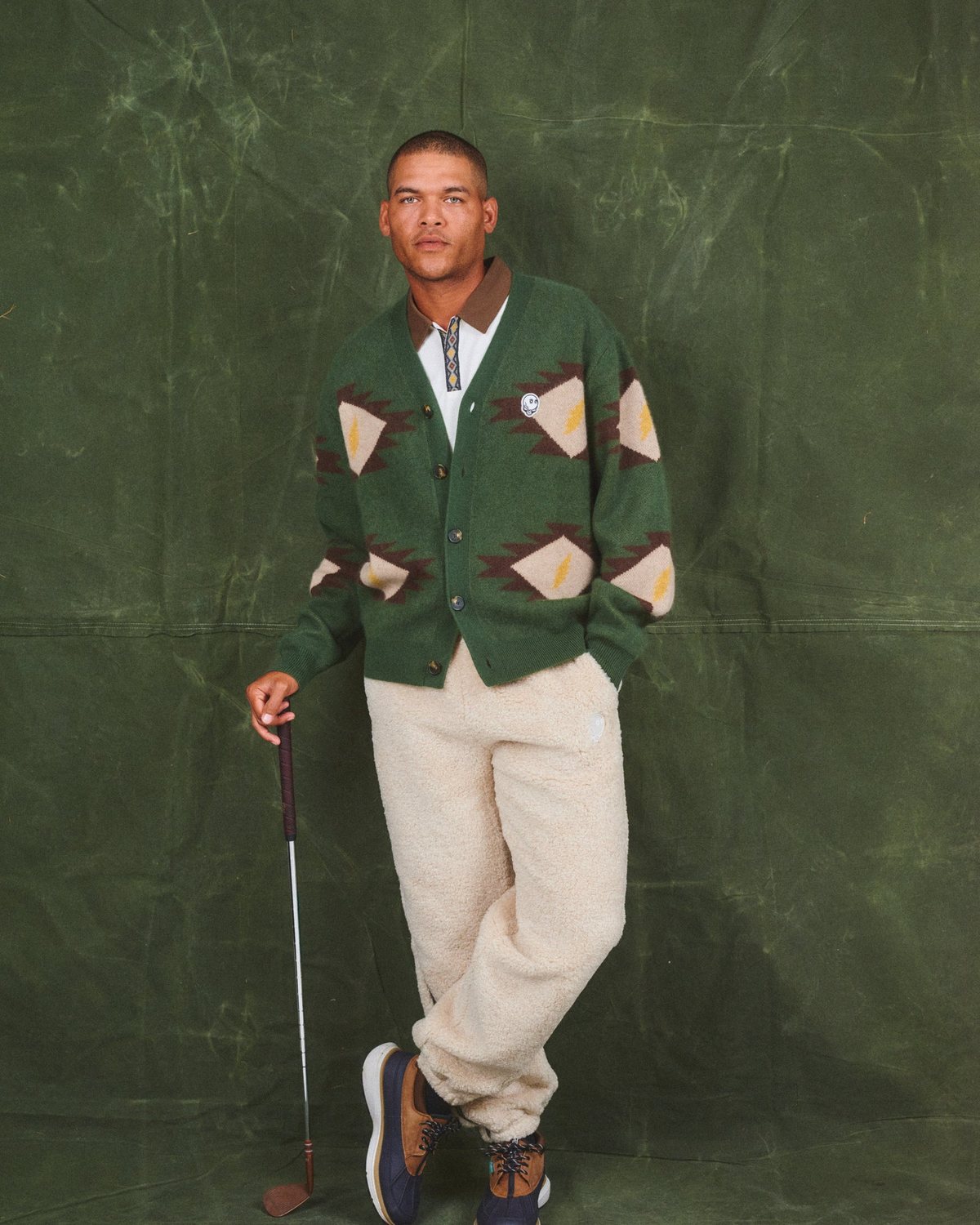 A model in the forest Long Vacation cardigan holding a golf club