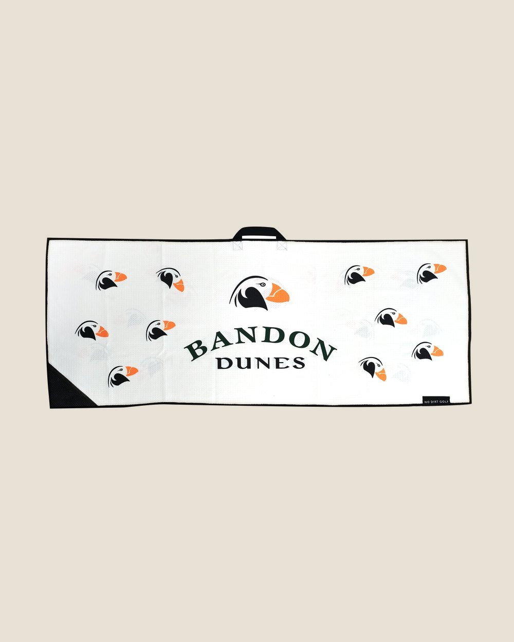 A white custom No Dirt towel printed with puffins and the Bandon Dunes name