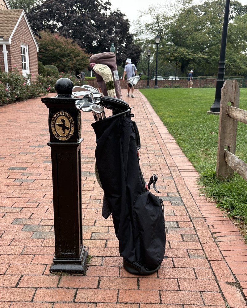 A stand bag leaning against the Bethpage State Park post on the brick path by the clubhouse