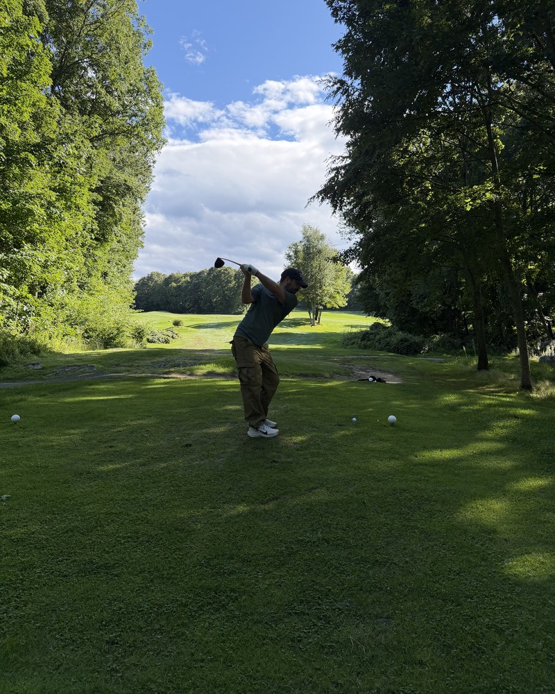 A golfer at the top of the backswing on a tree-framed tee at the Sedgewood Club