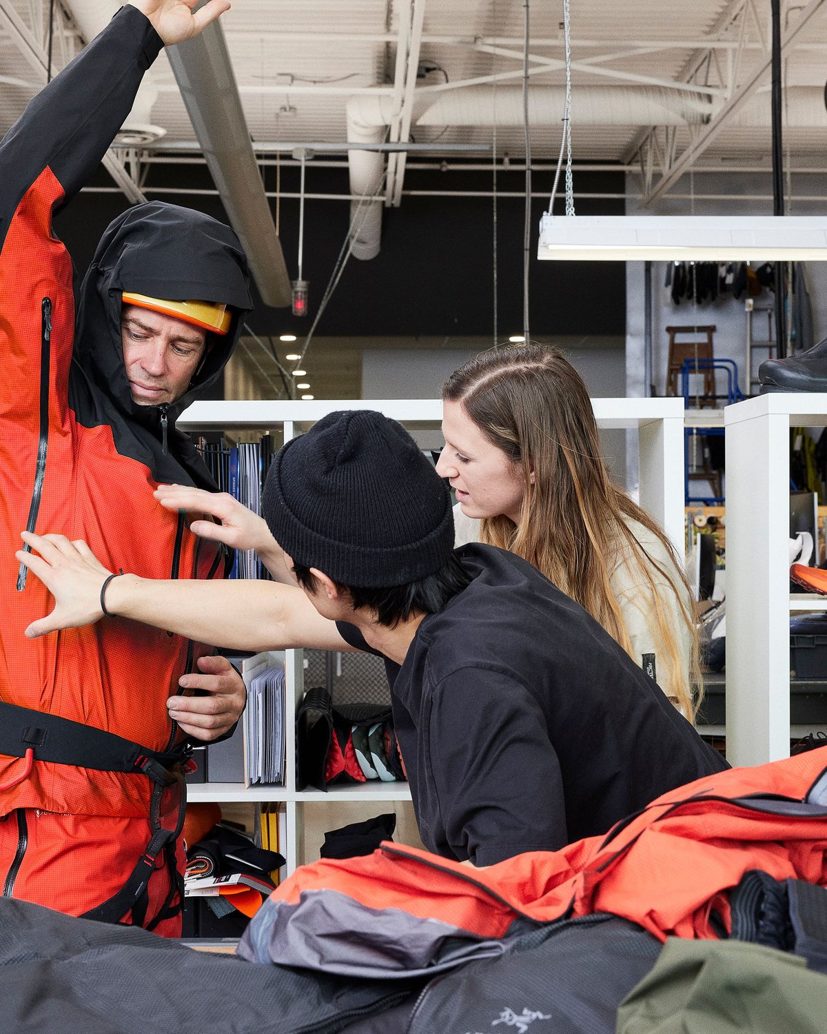 Designers fitting a red shell on a model inside the Arc’teryx design centre