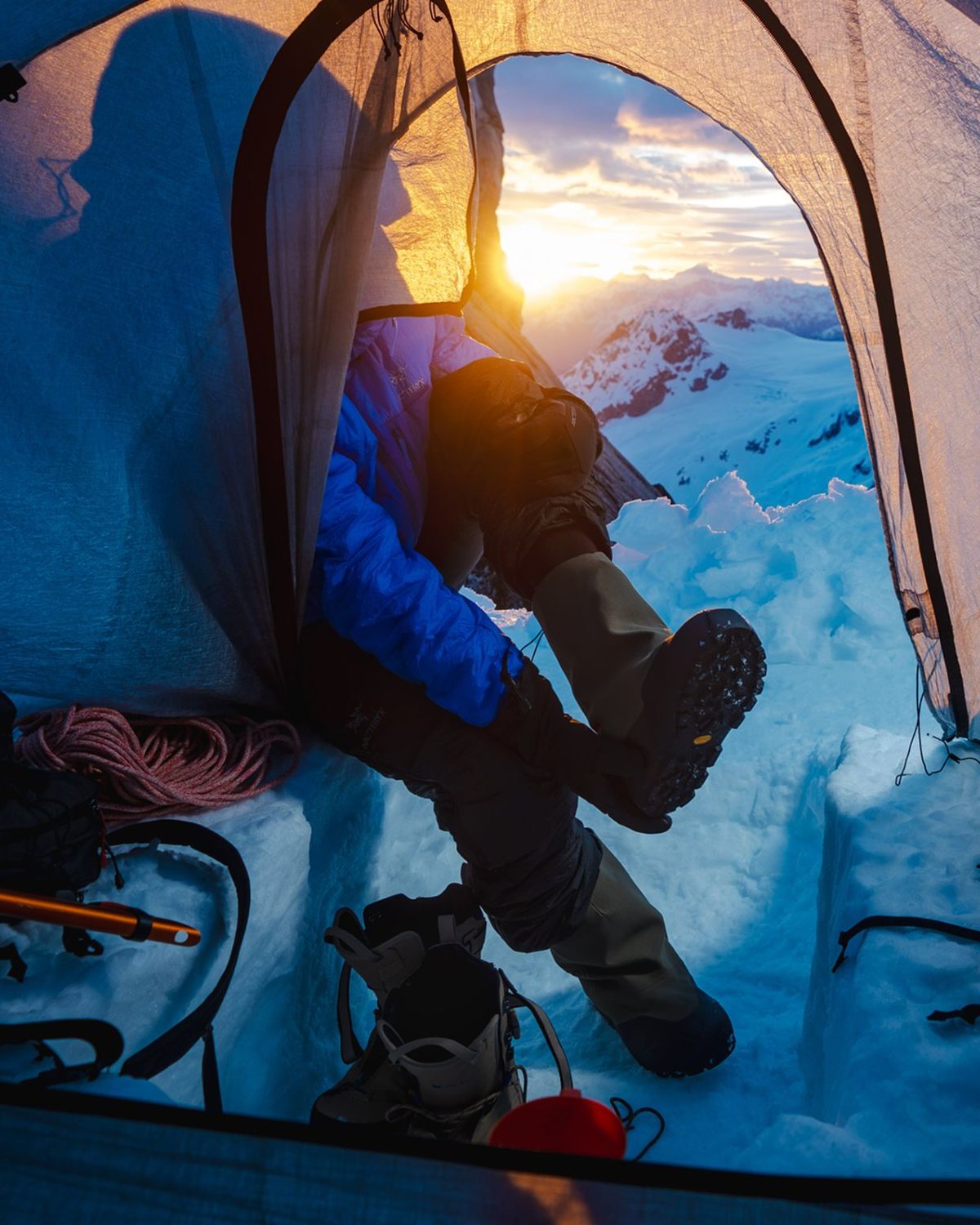 The view out of a tent door at sunset over snowy peaks