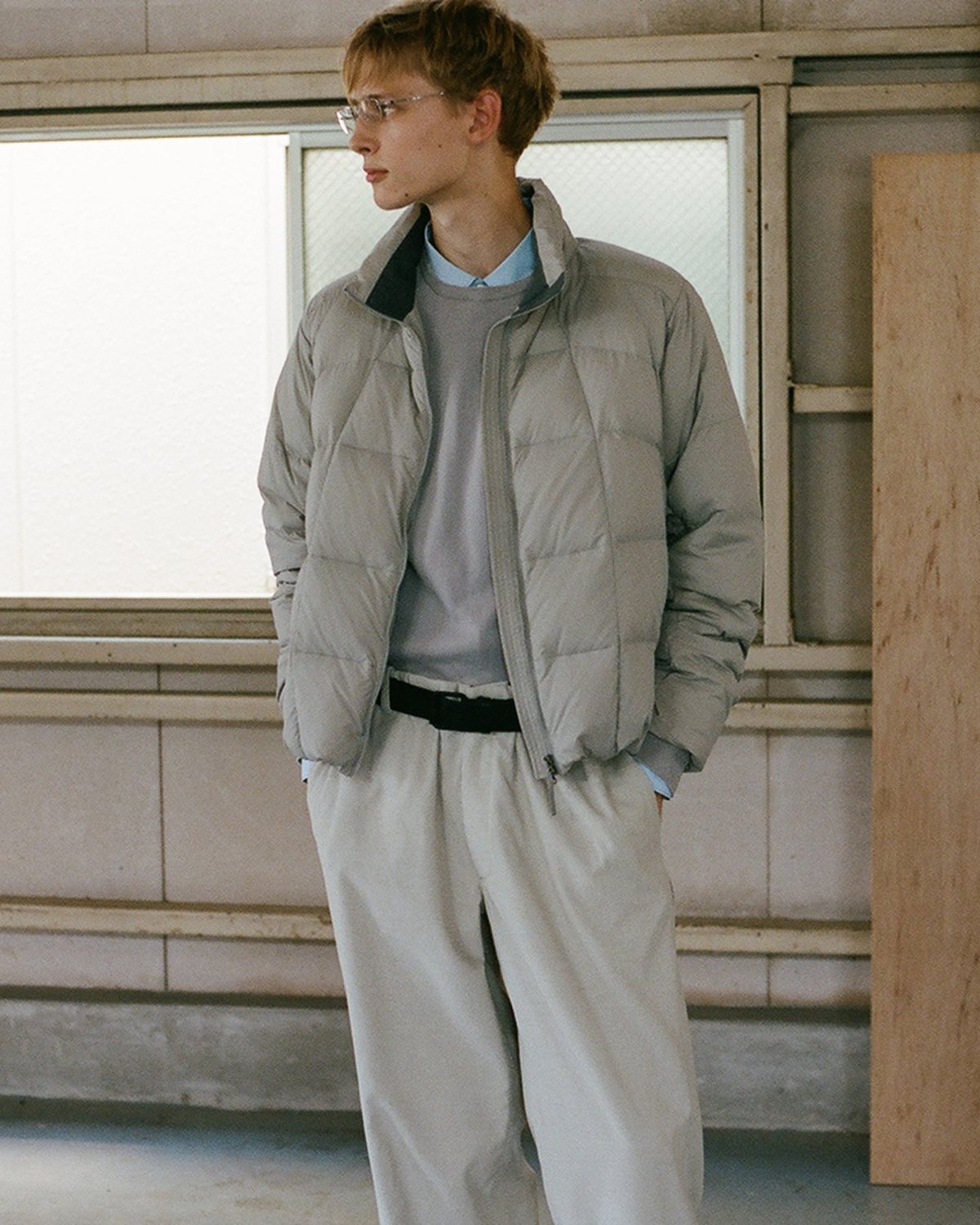 A model in a stone-colored down jacket and pleated trousers