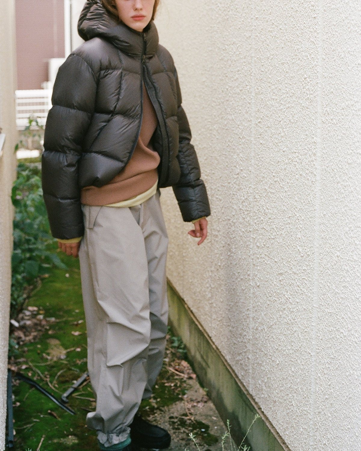 A model in a hooded down jacket walking along a wall