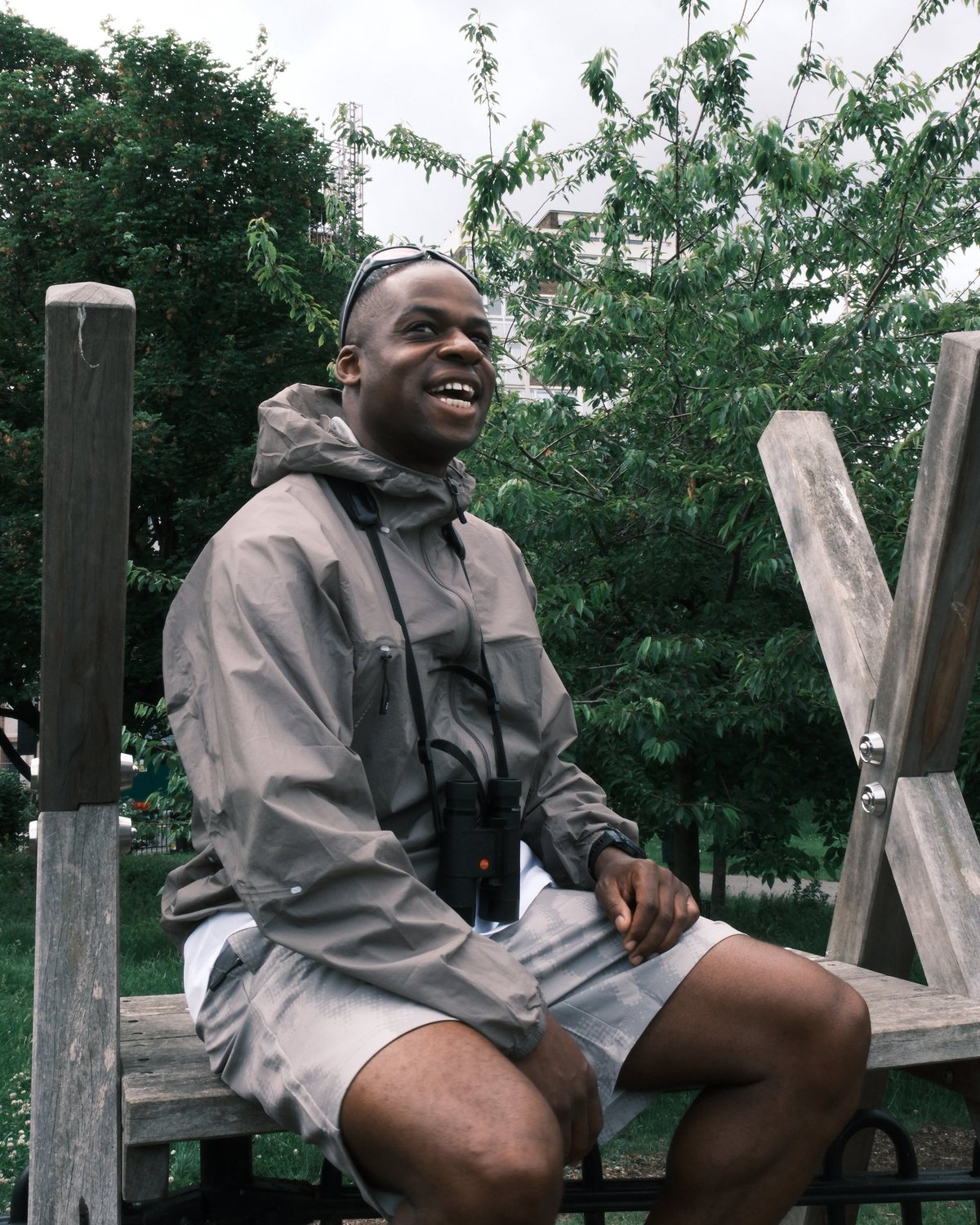 A man in a grey Purple Mountain Observatory shell on a park bench in London