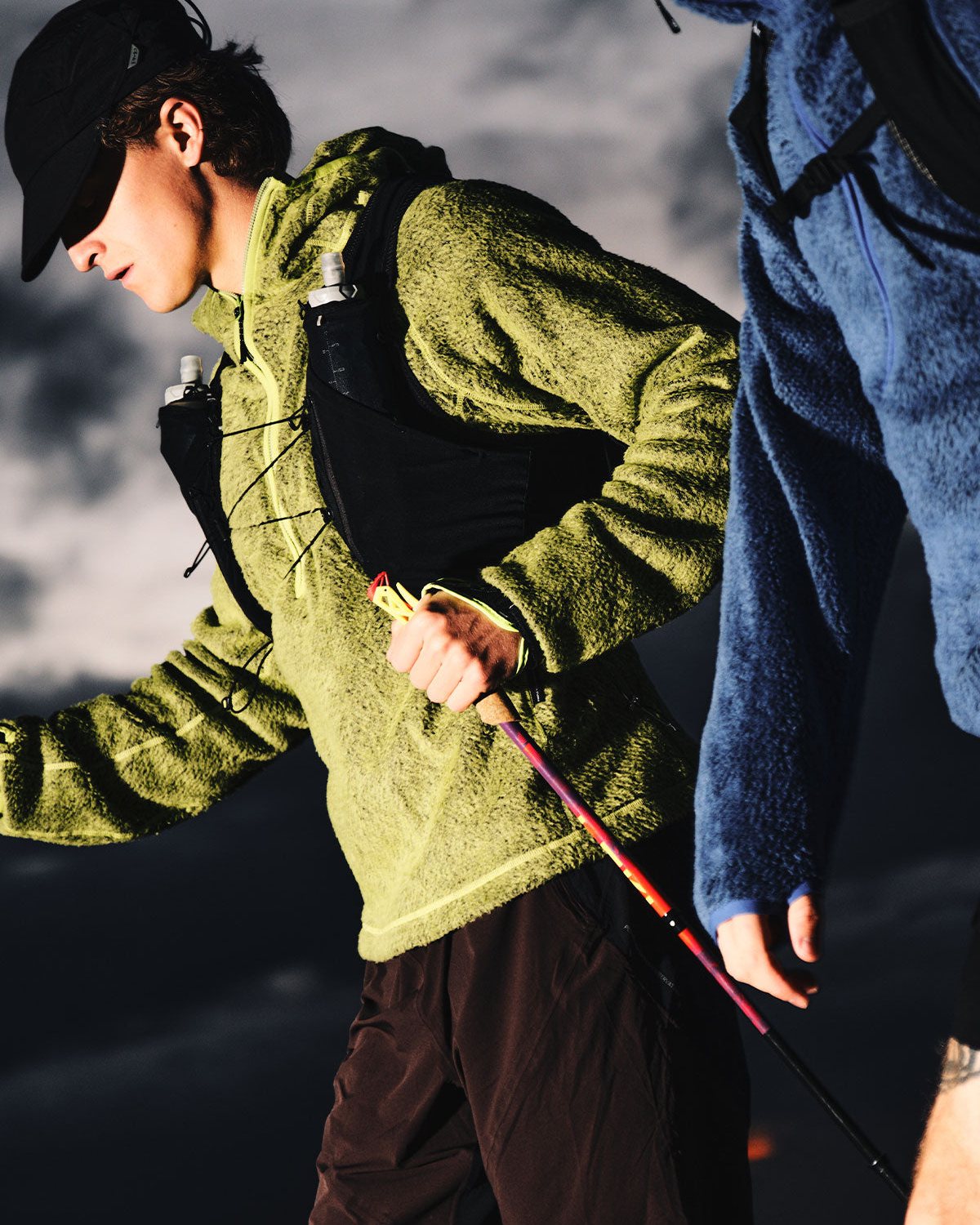 A hiker in a lime fleece on a mountain at dusk