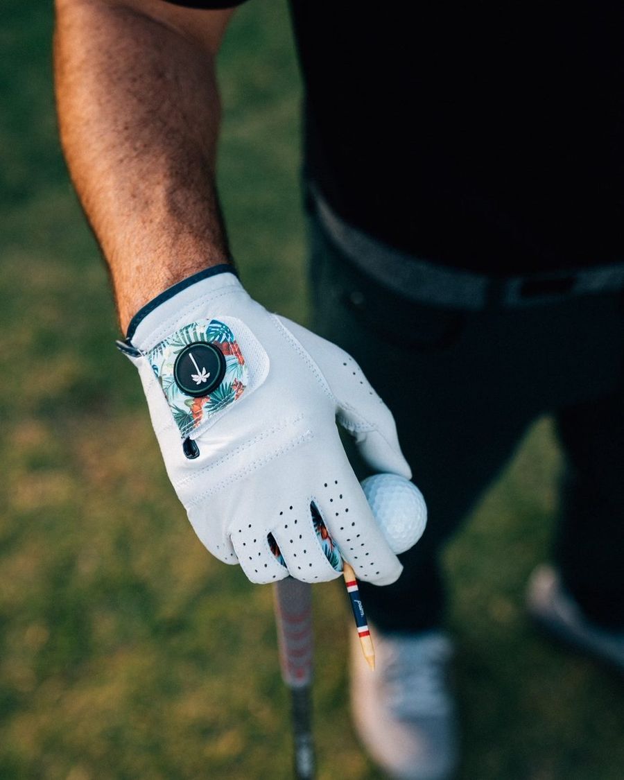 A Palm Barrels and Birdies glove on a golfer's hand at the course