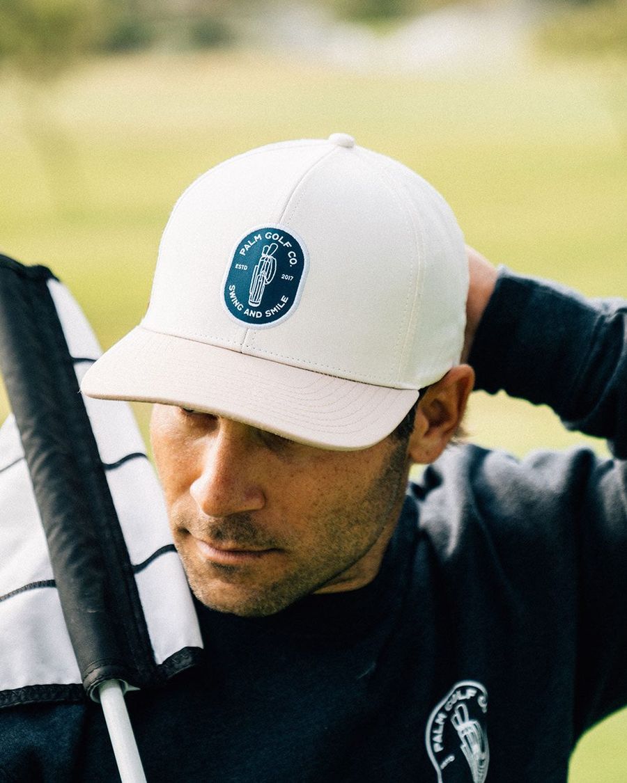 A golfer in a Palm snapback at his bag