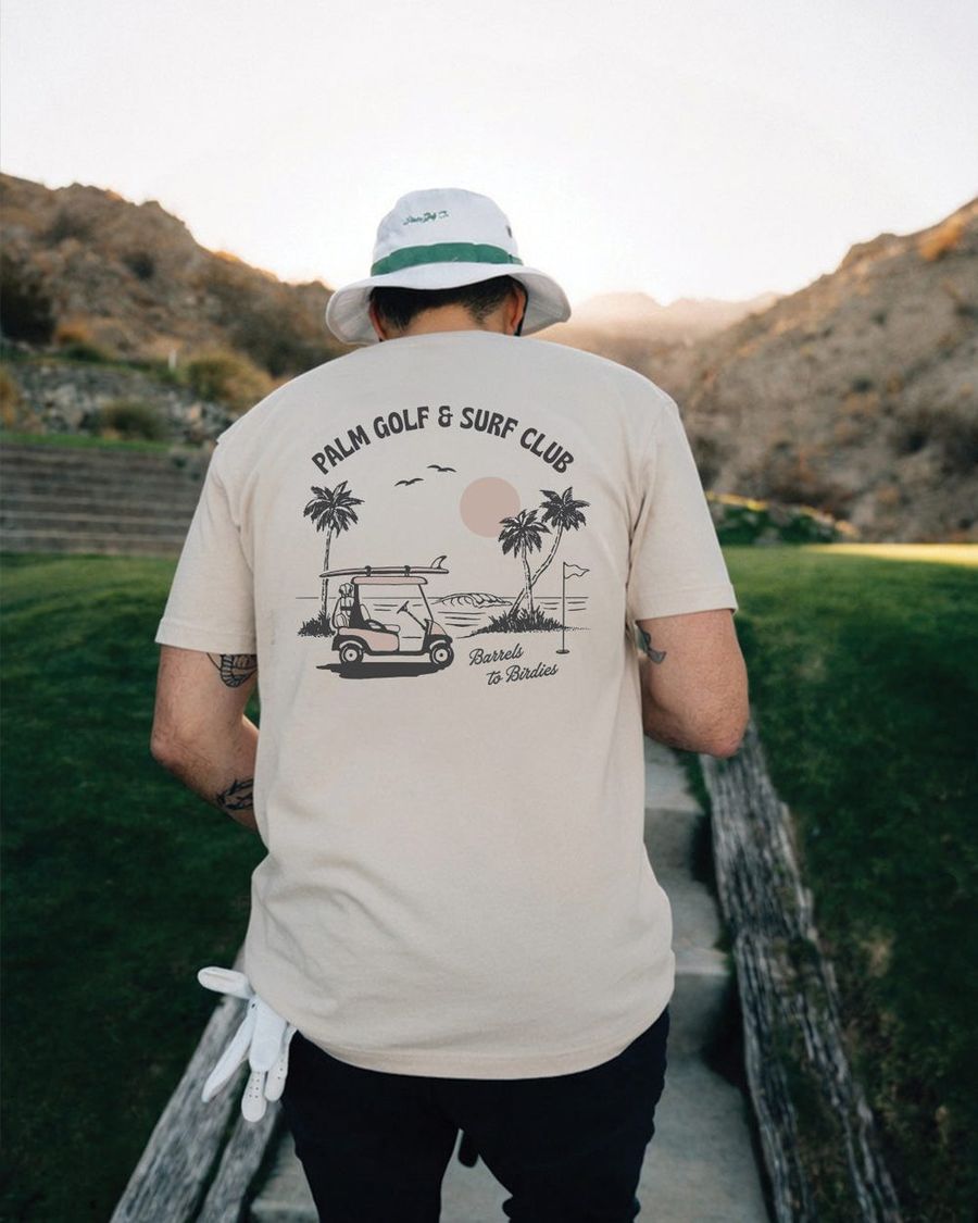 A golfer in the Palm Cart Cruisin' tee walking with his bag