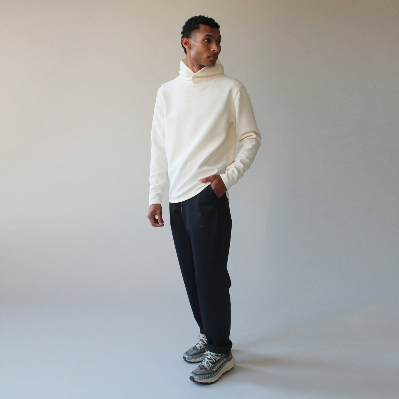 A model in a cream hoodie and dark navy Sentinel trousers, from the FW26 lookbook
