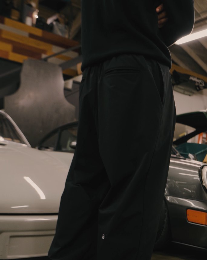 A man in black Science pants walking between classic cars
