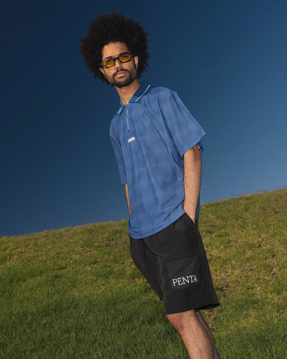 A man in a blue polo and black Hazard Shorts on a grassy hill