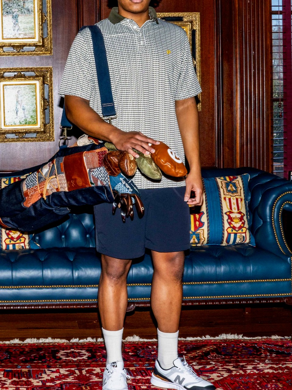 A golfer with a carry bag in a striped polo and navy shorts in a clubroom
