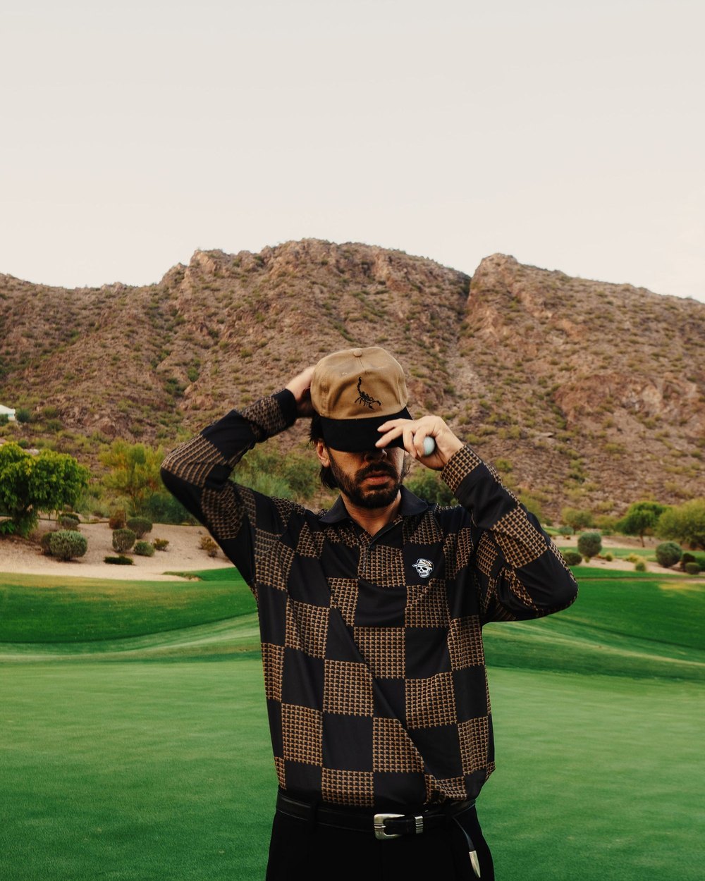 A man in a brown checkerboard Devereux knit on a desert golf course