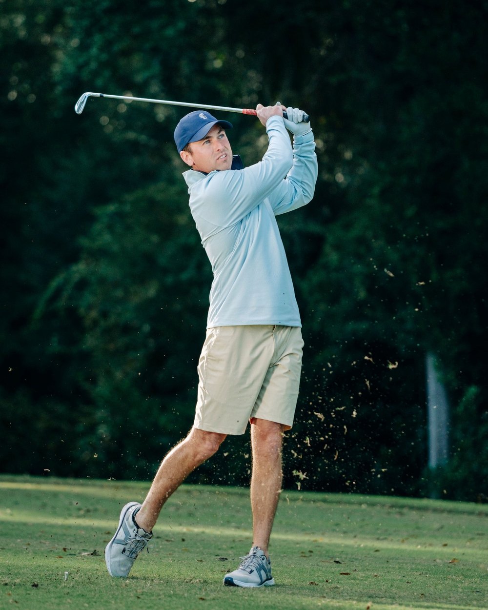 A golfer in a pale-blue Juniper & James quarter-zip at the finish of an iron swing