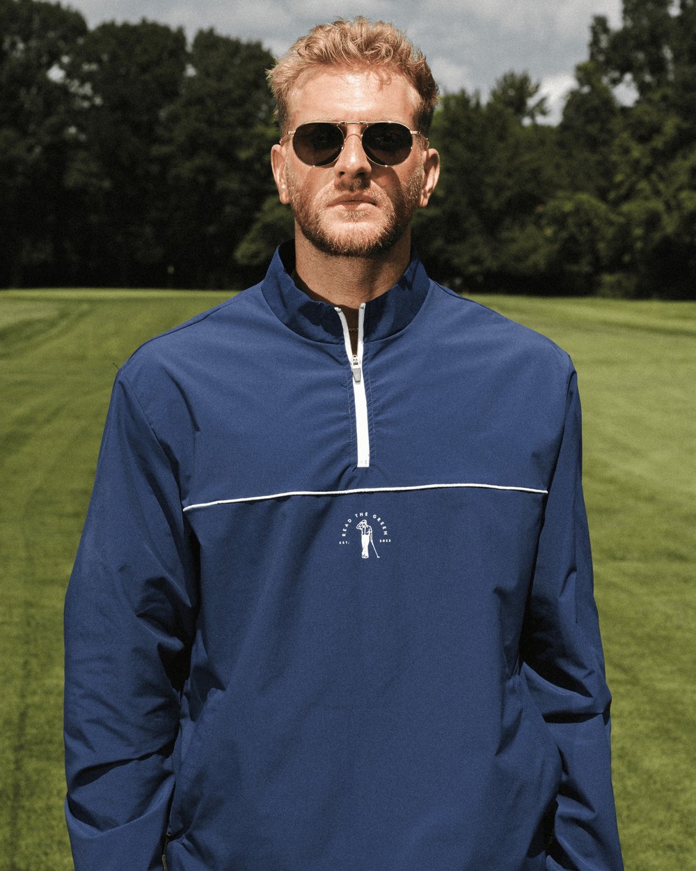A golfer in a navy piped Read the Green half-zip windshirt on a fairway