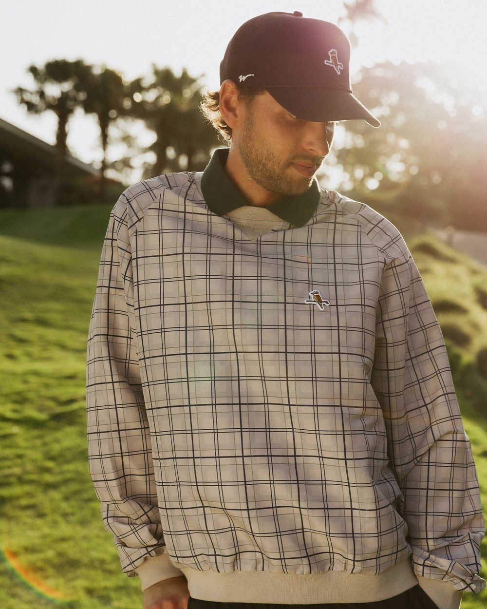 A golfer in a plaid Walker windshirt on a sunlit course