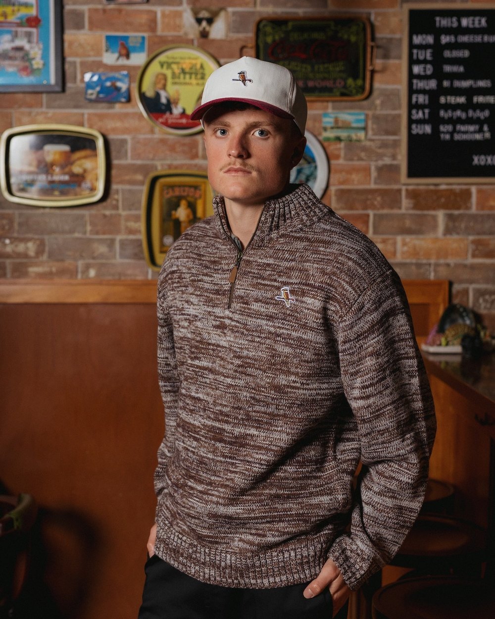 A man in a brown space-dye Walker knit quarter-zip in a pub