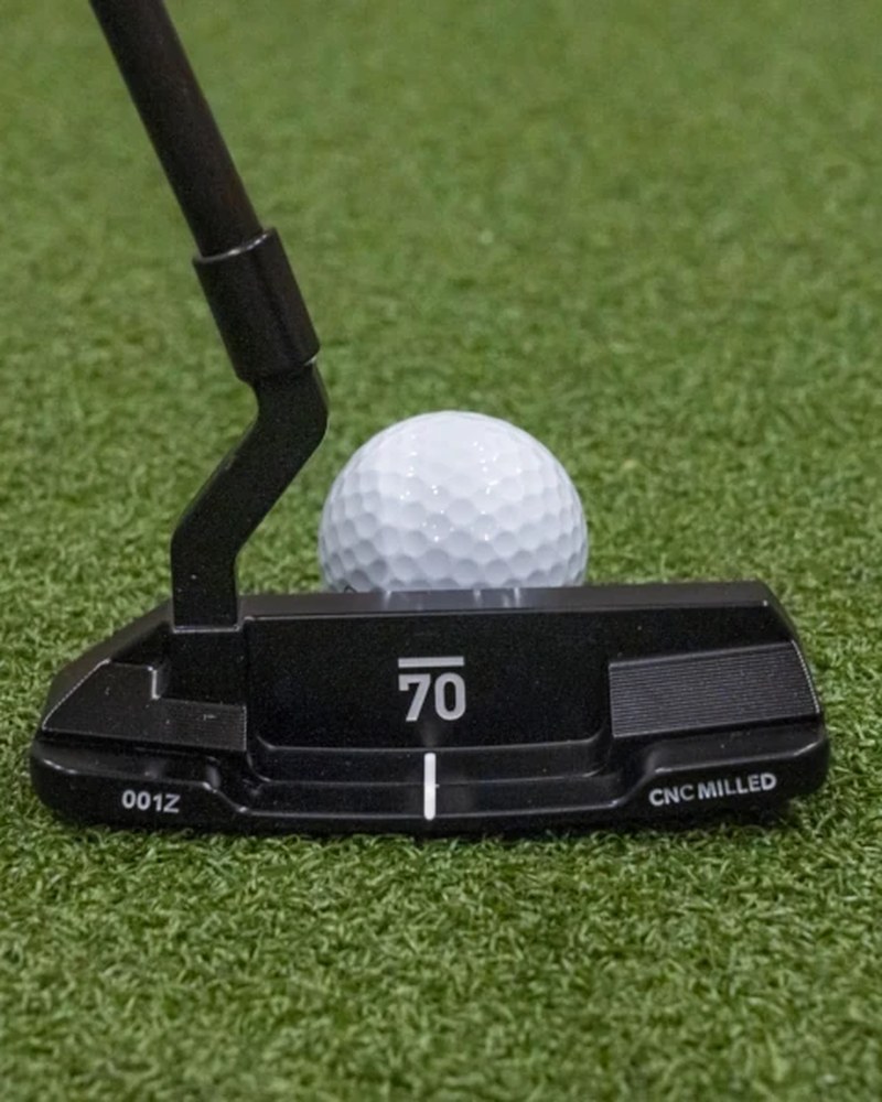 The Sub 70 Sycamore 001Z zero torque blade putter at address behind a golf ball on a green