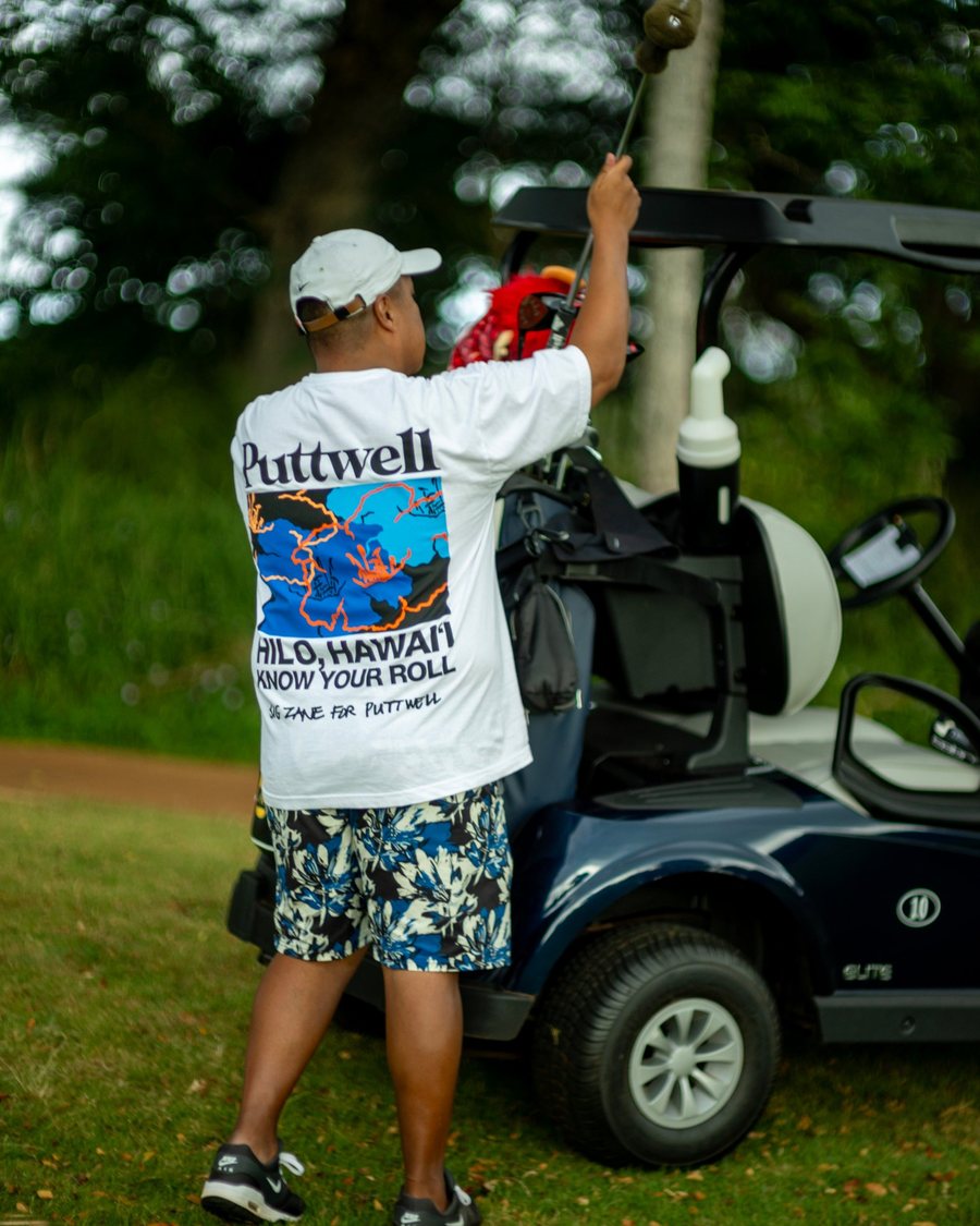 A golfer in a Puttwell tee by a golf cart