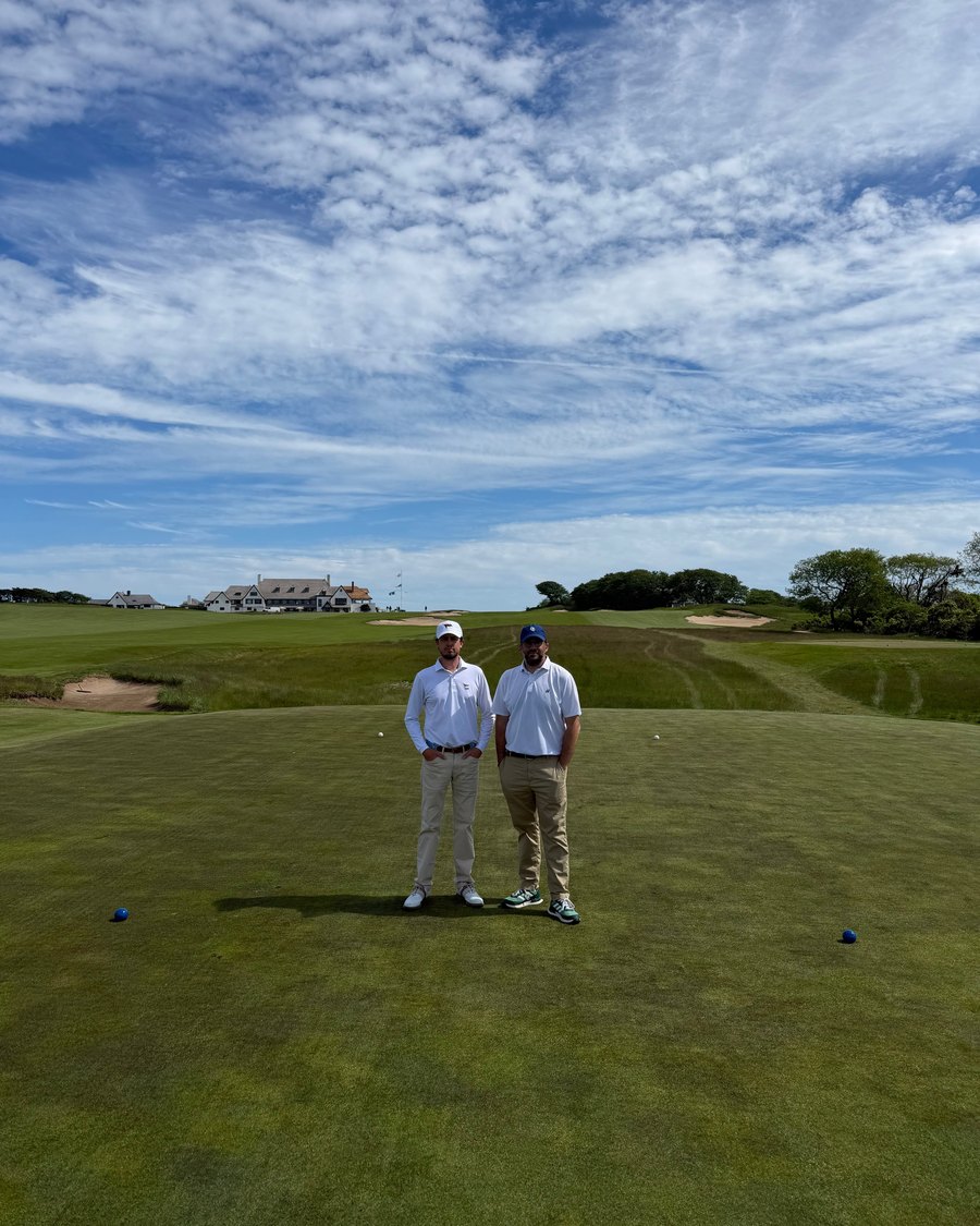 Two golfers standing on a tee under a cloudy sky