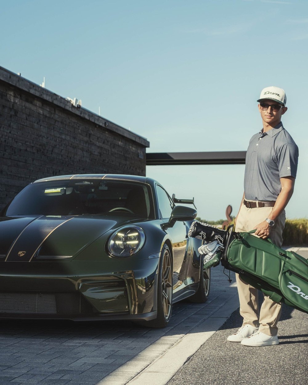 A golfer with a green DRVN bag standing beside a green Porsche