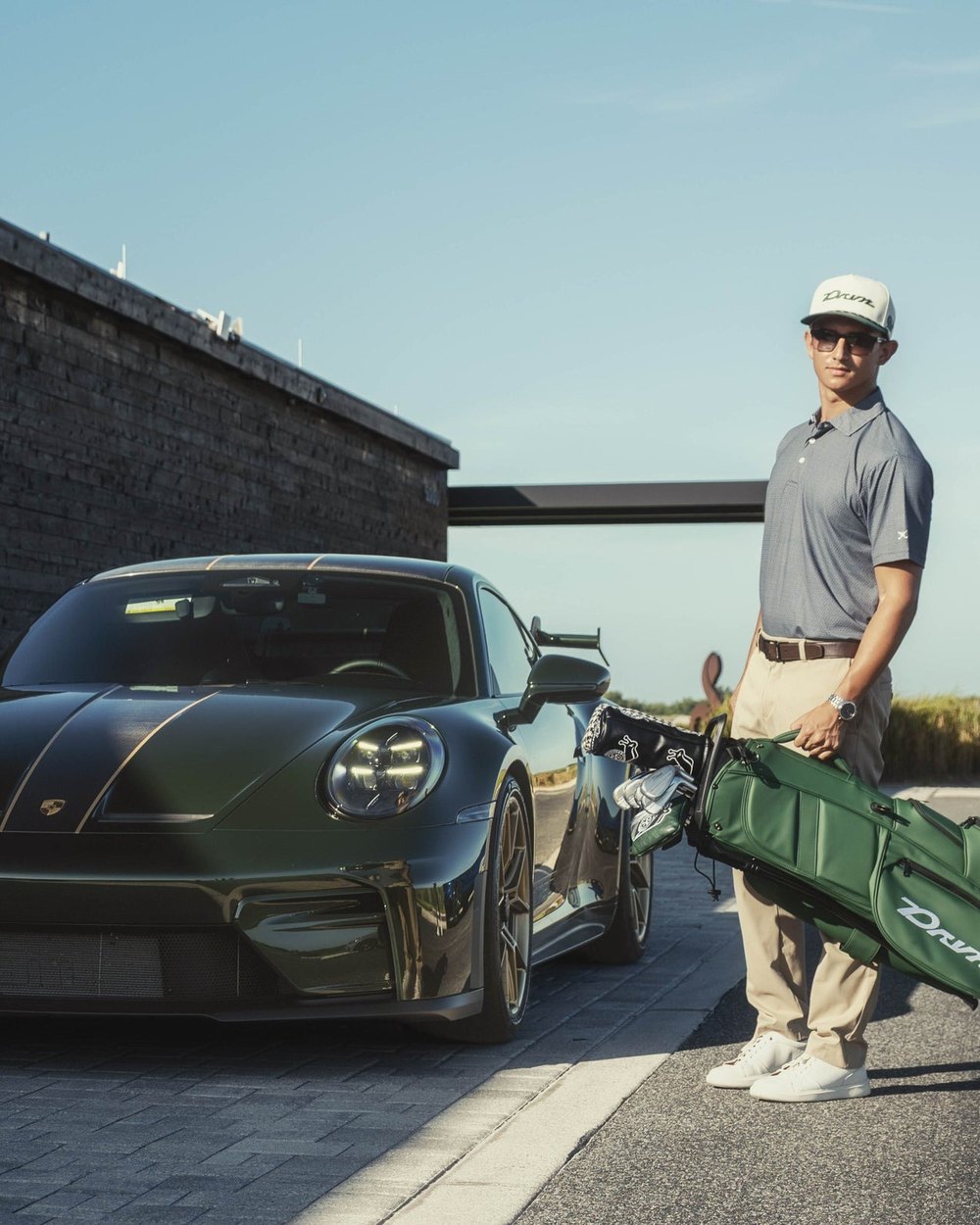 A golfer with a green DRVN golf bag standing beside a green Porsche