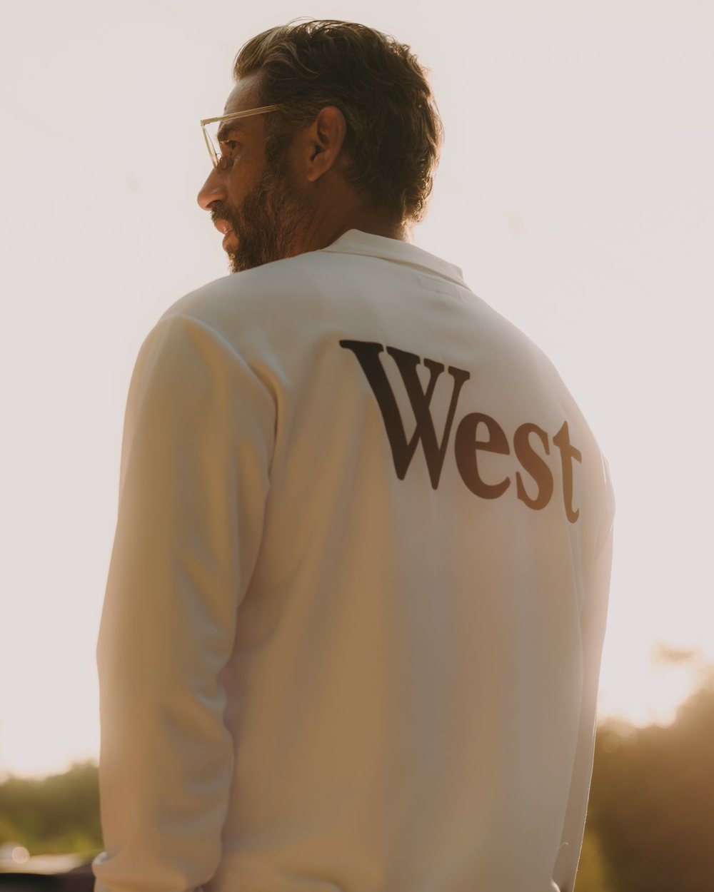 A man from behind at sunset in a cream Aberdeen West jacket with West across the back