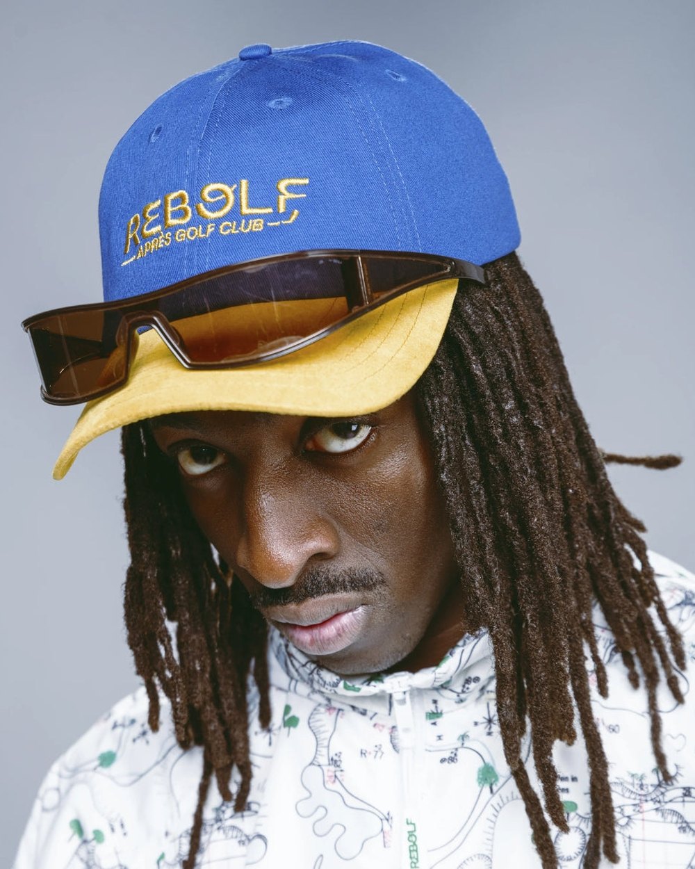 A model in a blue and yellow Rebolf cap and orange sunglasses