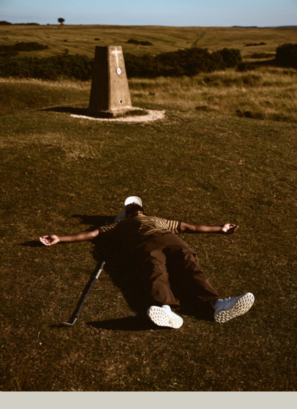 Golfer sprawled on a links fairway next to a marker post