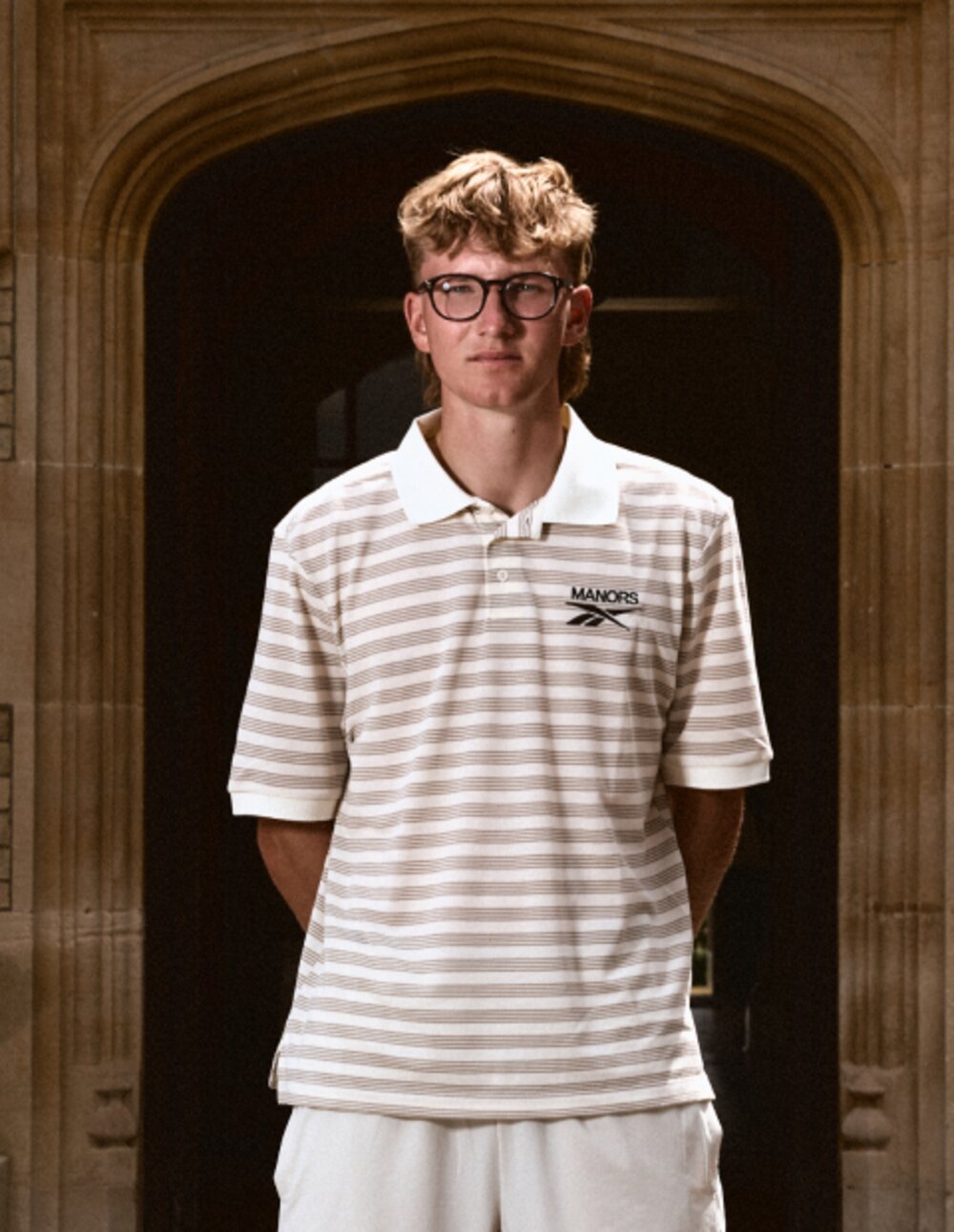 Reebok x Manors II striped pique polo shot in a stone doorway
