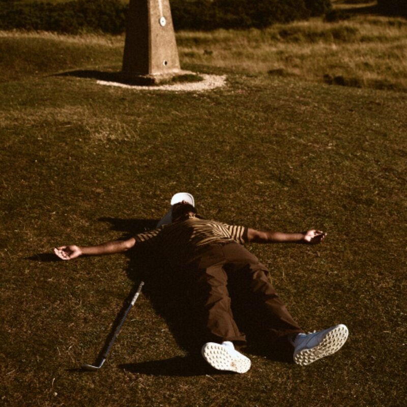 Golfer sprawled on a links fairway beside a marker post, Reebok x Manors II campaign