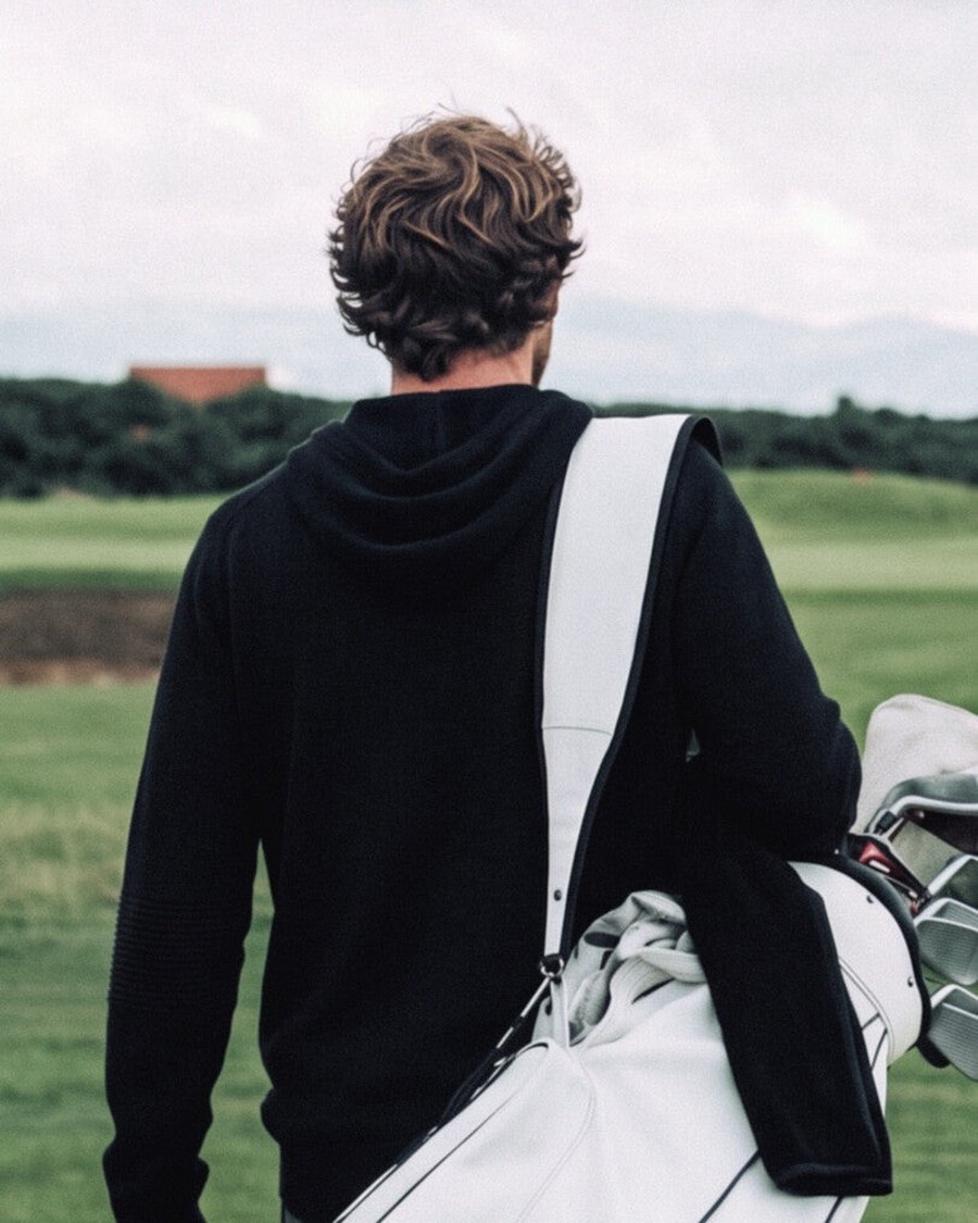 A golfer walking off with a carry bag over a black hoodie