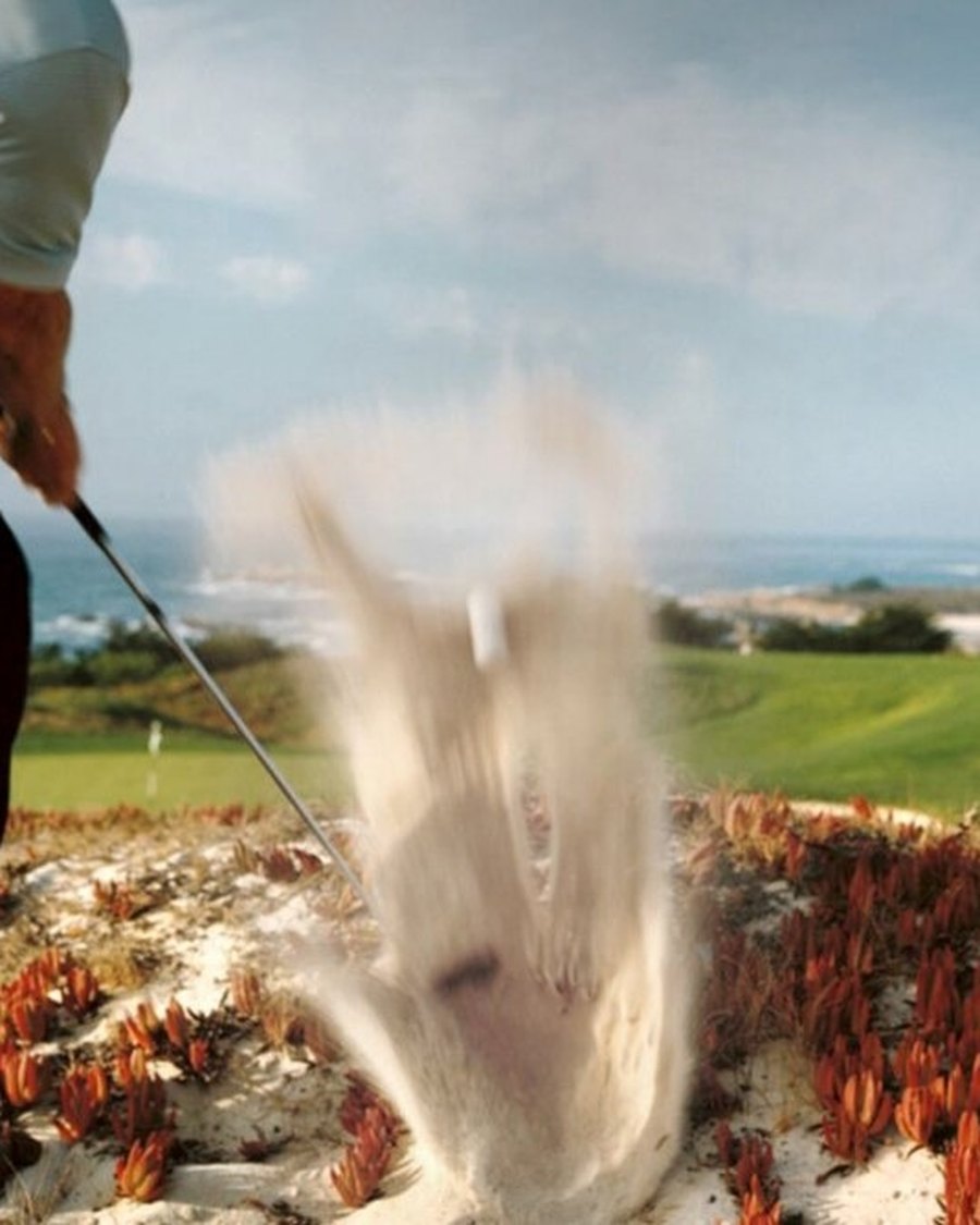 A bunker shot spraying sand on a seaside course